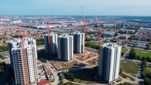 Clădiri moderne în construcție și macarale în oraș.